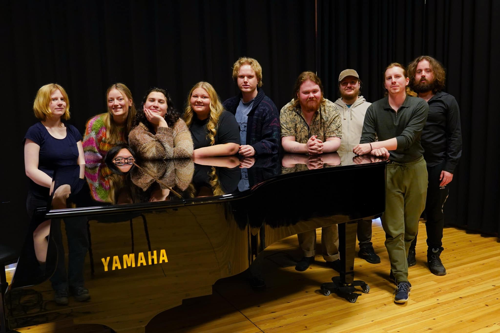 Folk som står bak et piano.
