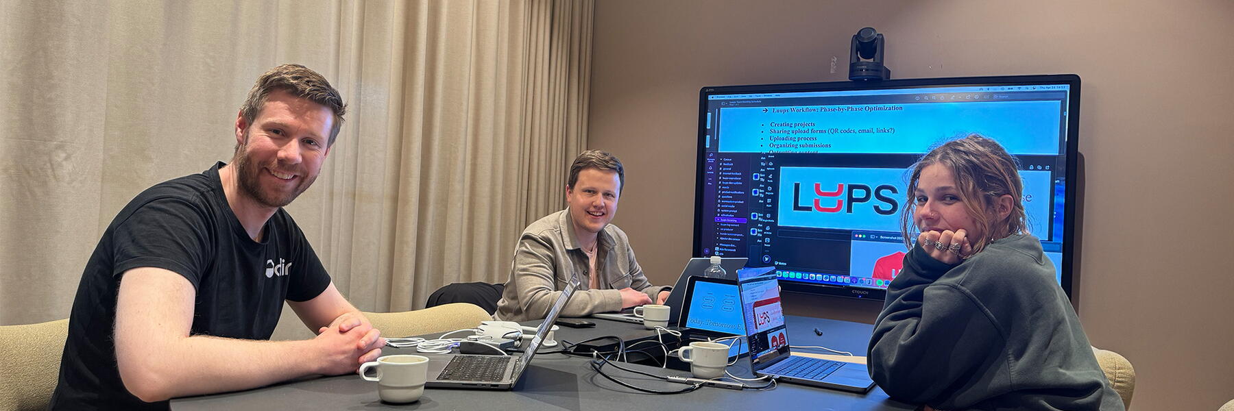 Two menn and a woman sitting around a conference table.