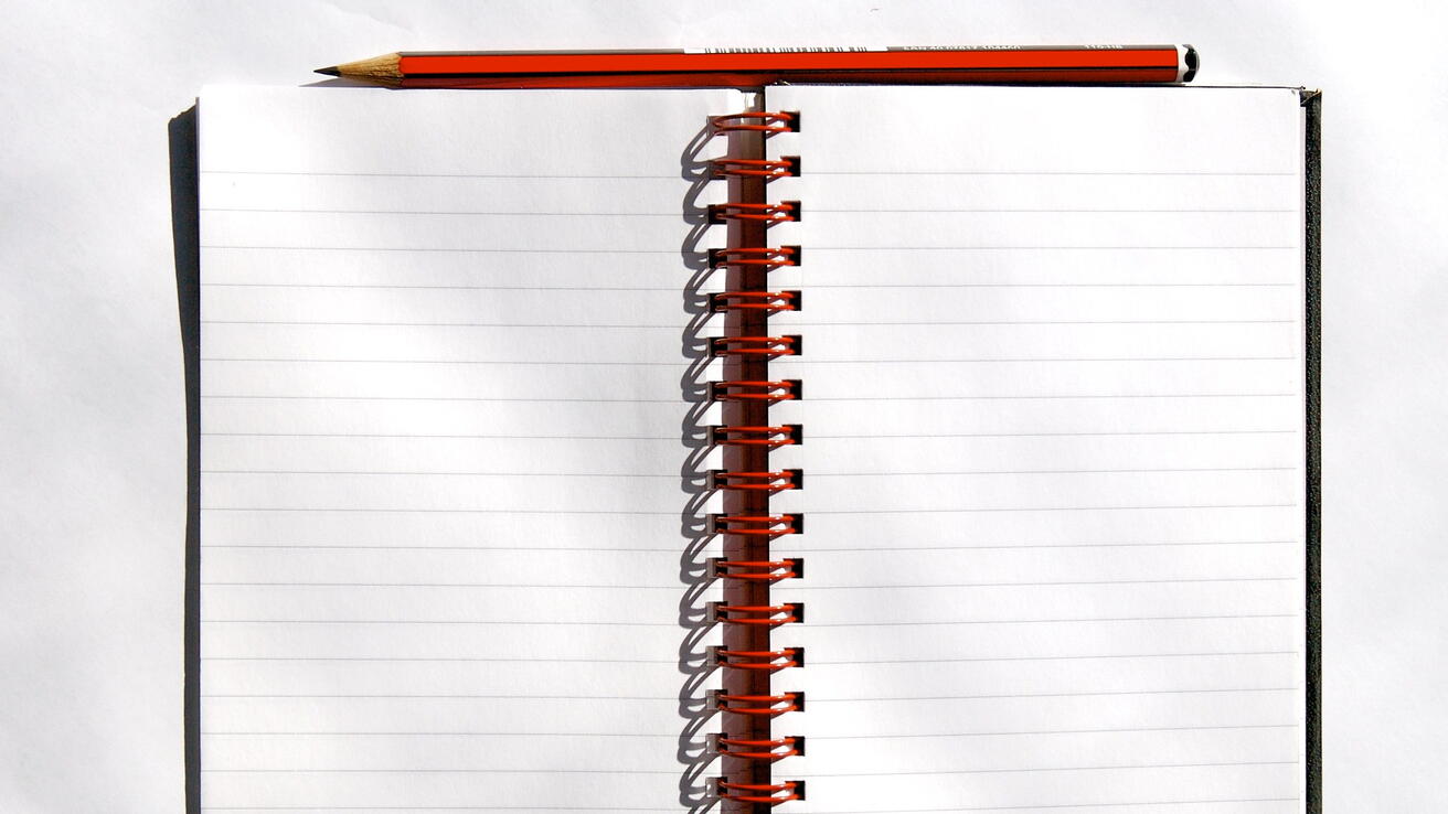 Open notebook with pencil. Stock photo.