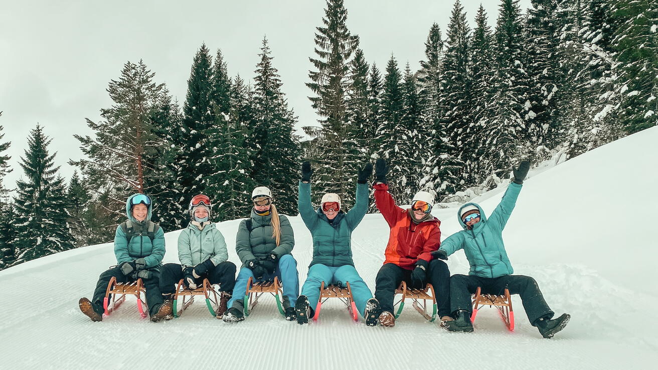 En gjeng på akebrett i snørike omgivelser.