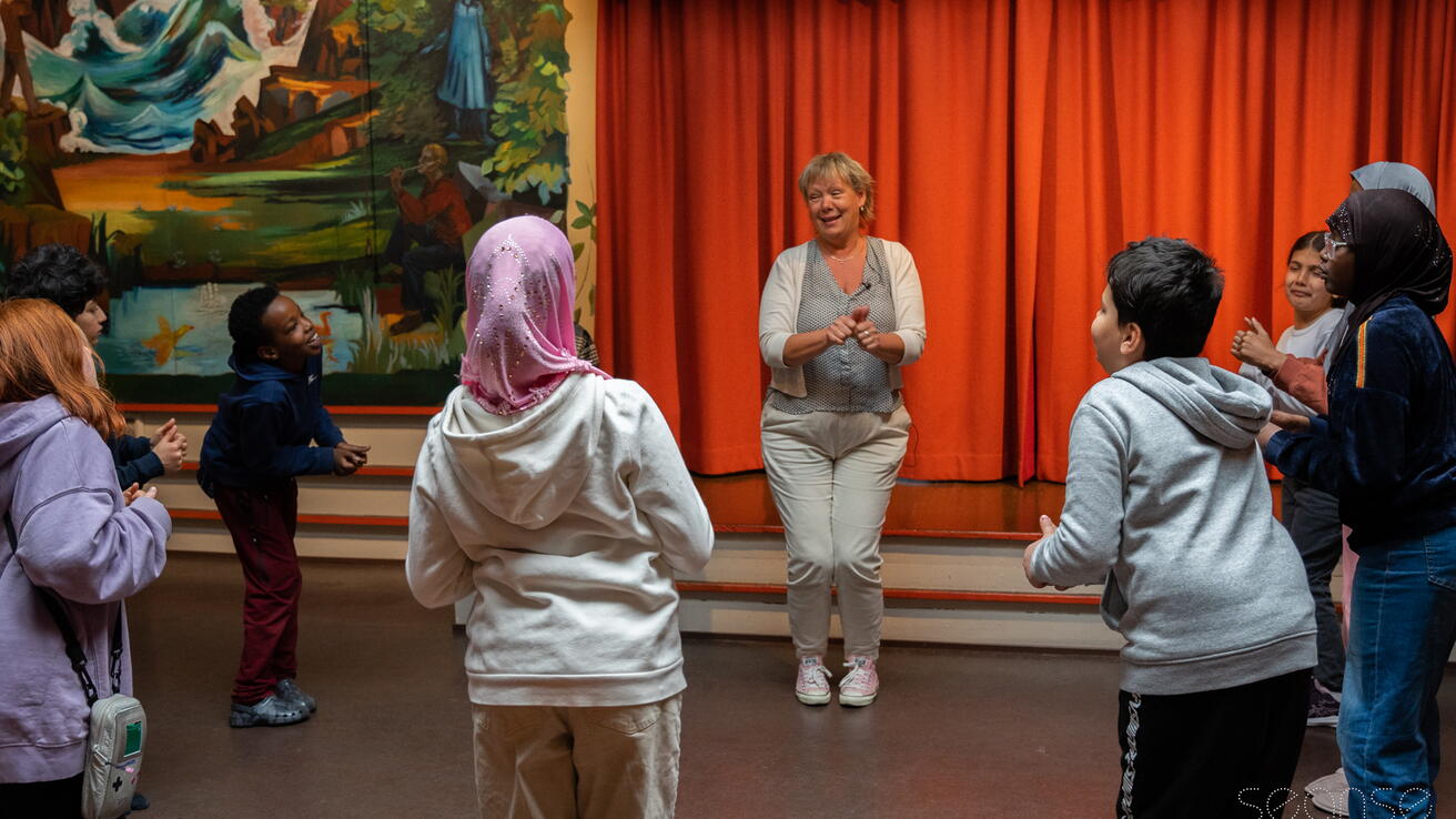 Dame og flere barn står i en ring