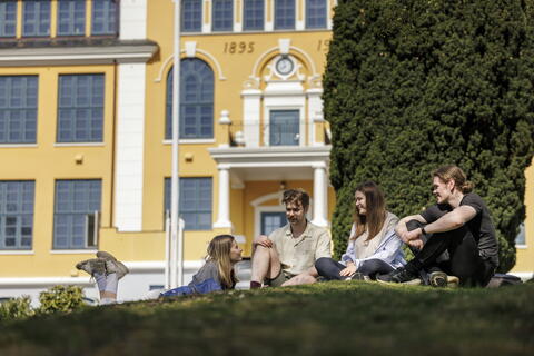 Studenter som sitter fremfor Kaarstad-bygget