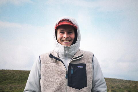 Mann med rød caps og hette ute i naturen.