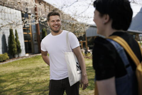 En smilende mannlig student som snakker med en kvinnelig student 