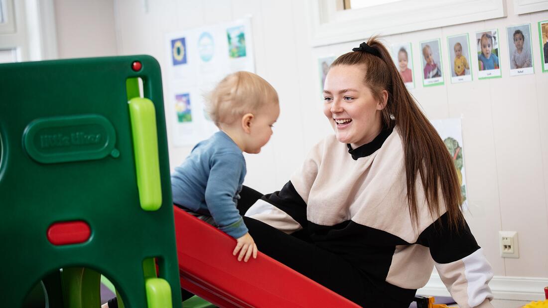 Barnehagelærar og barn på sklie.